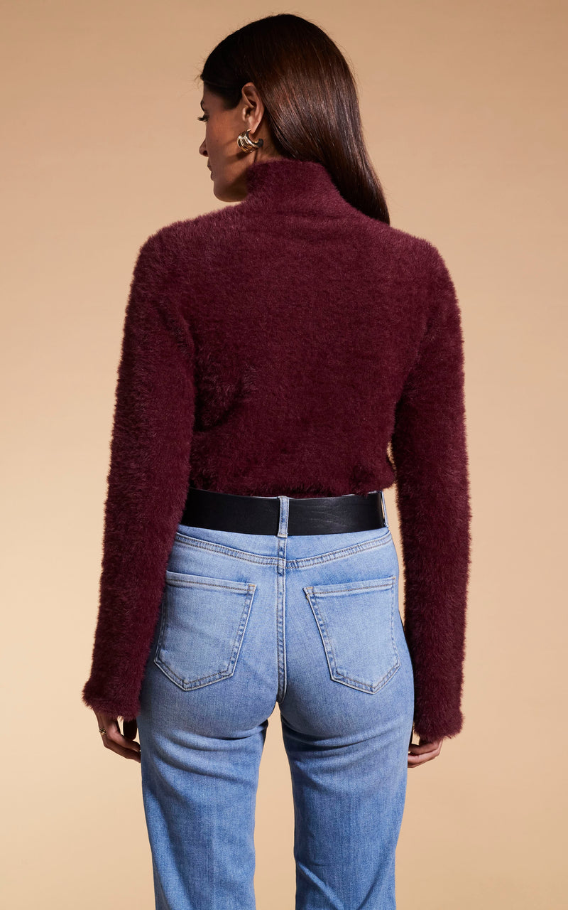 Model faces back wearing Dancing Leopard burgunday knitted jumper and jeans