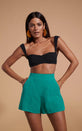  Dancing Leopard model wearing Lola Linen Shorts In Vivid Green and a black top posed with hands in pockets