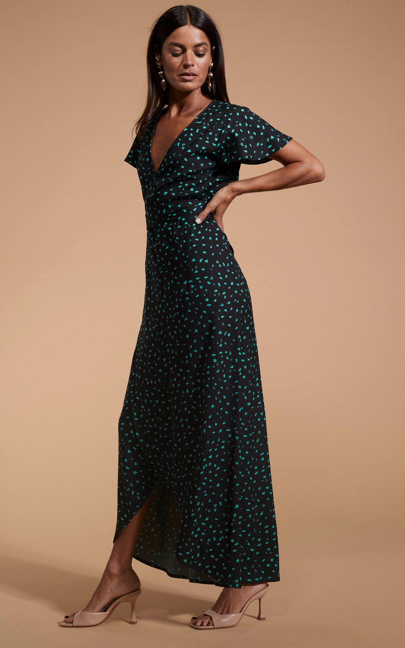 Dancing Leopard model wearing Cayenne Dress In Abstract Green On Black facing side on with hands on hips