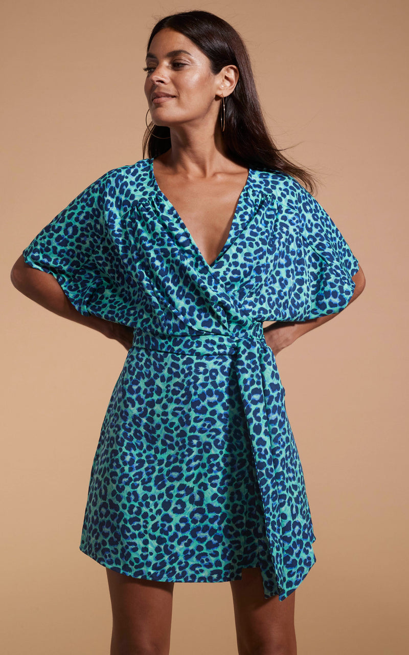 Dancing Leopard model wearing Kansas Mini Wrap Dress In Turquoise Leopard posed with hands behind back