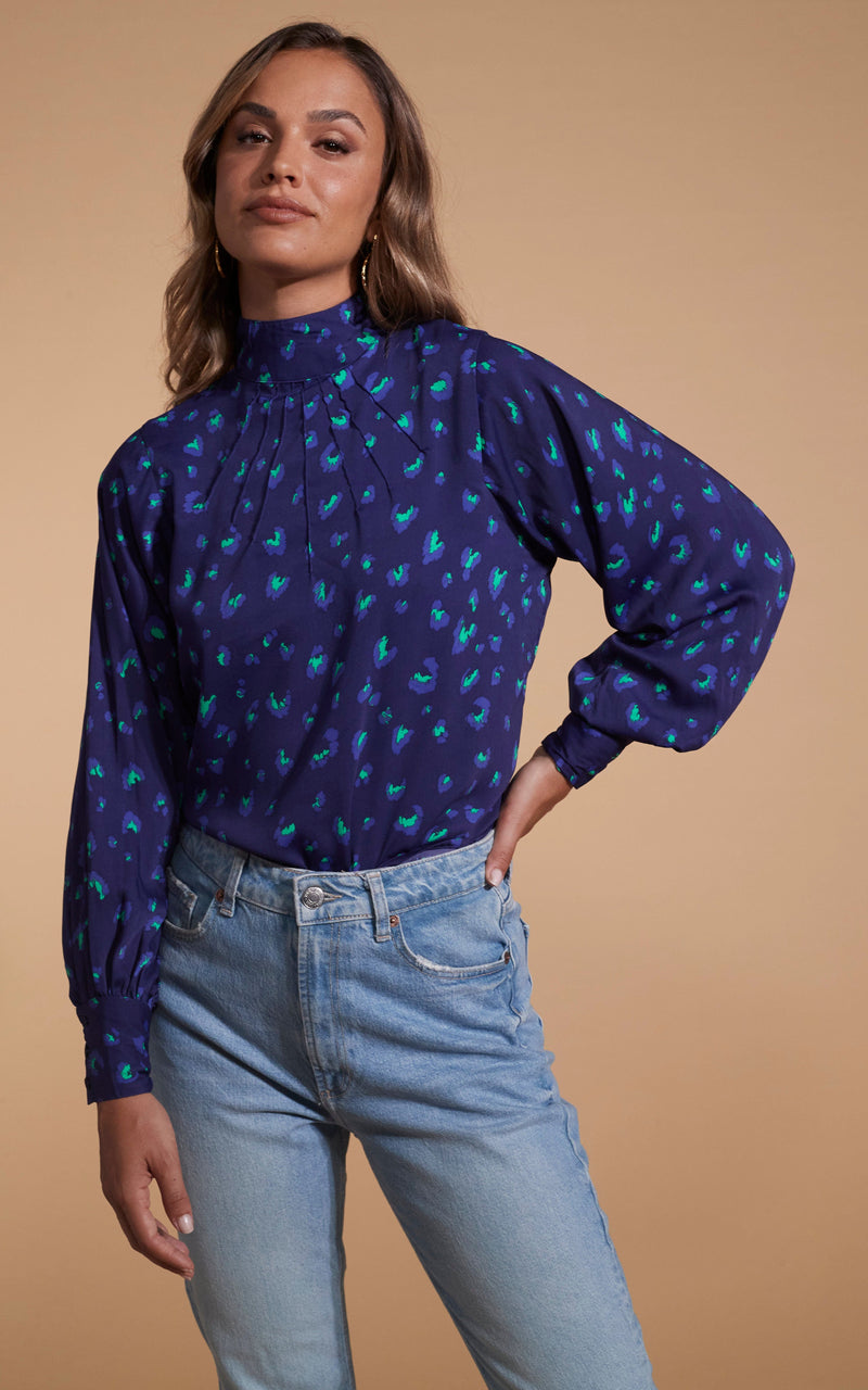 Dancing Leopard model wearing Margo Pintuck Blouse in Abstract Purple on Navy posed with hand hip