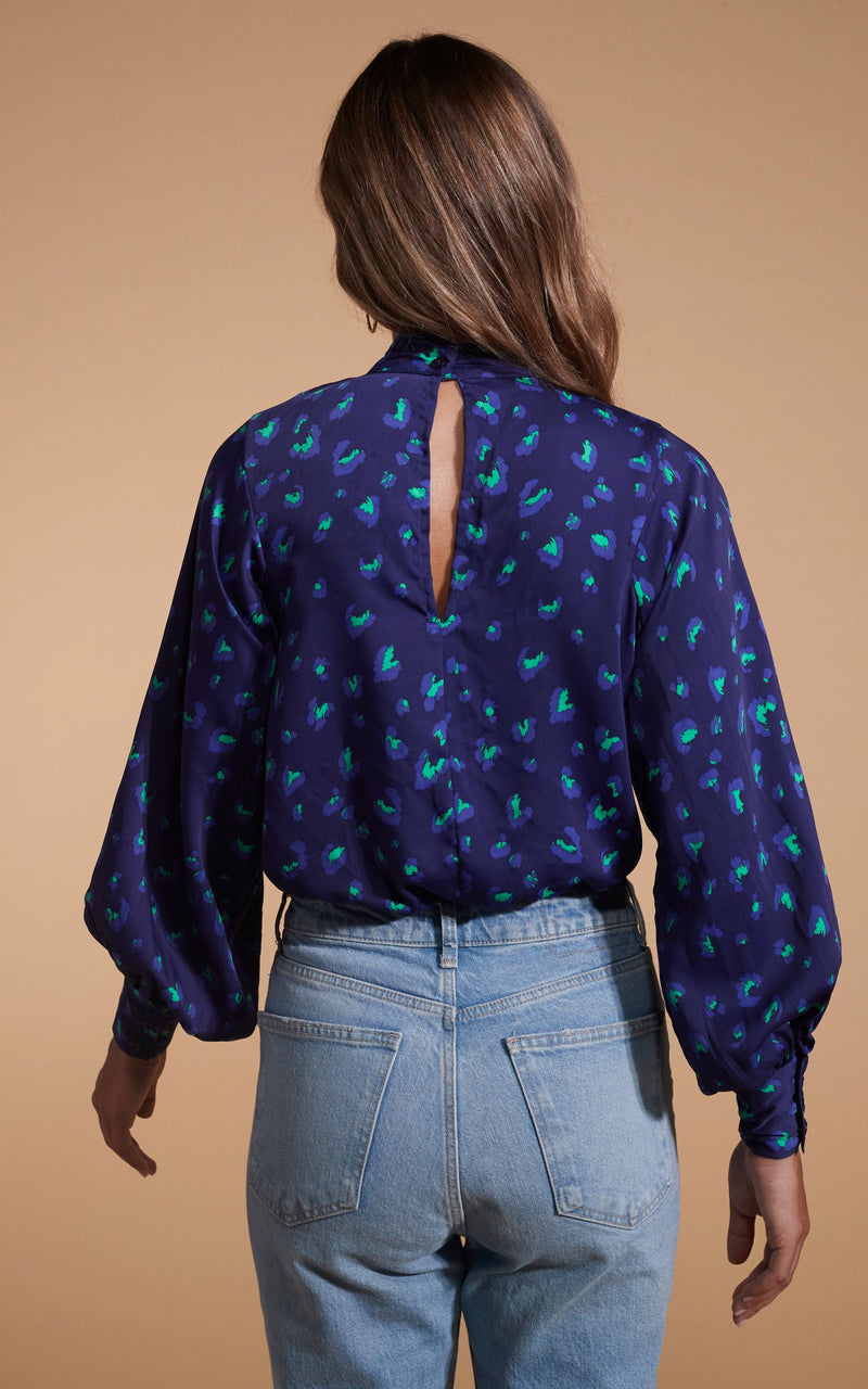 Dancing Leopard model wearing Margo Pintuck Blouse in Abstract Purple on Navy facing away to show back of blouse
