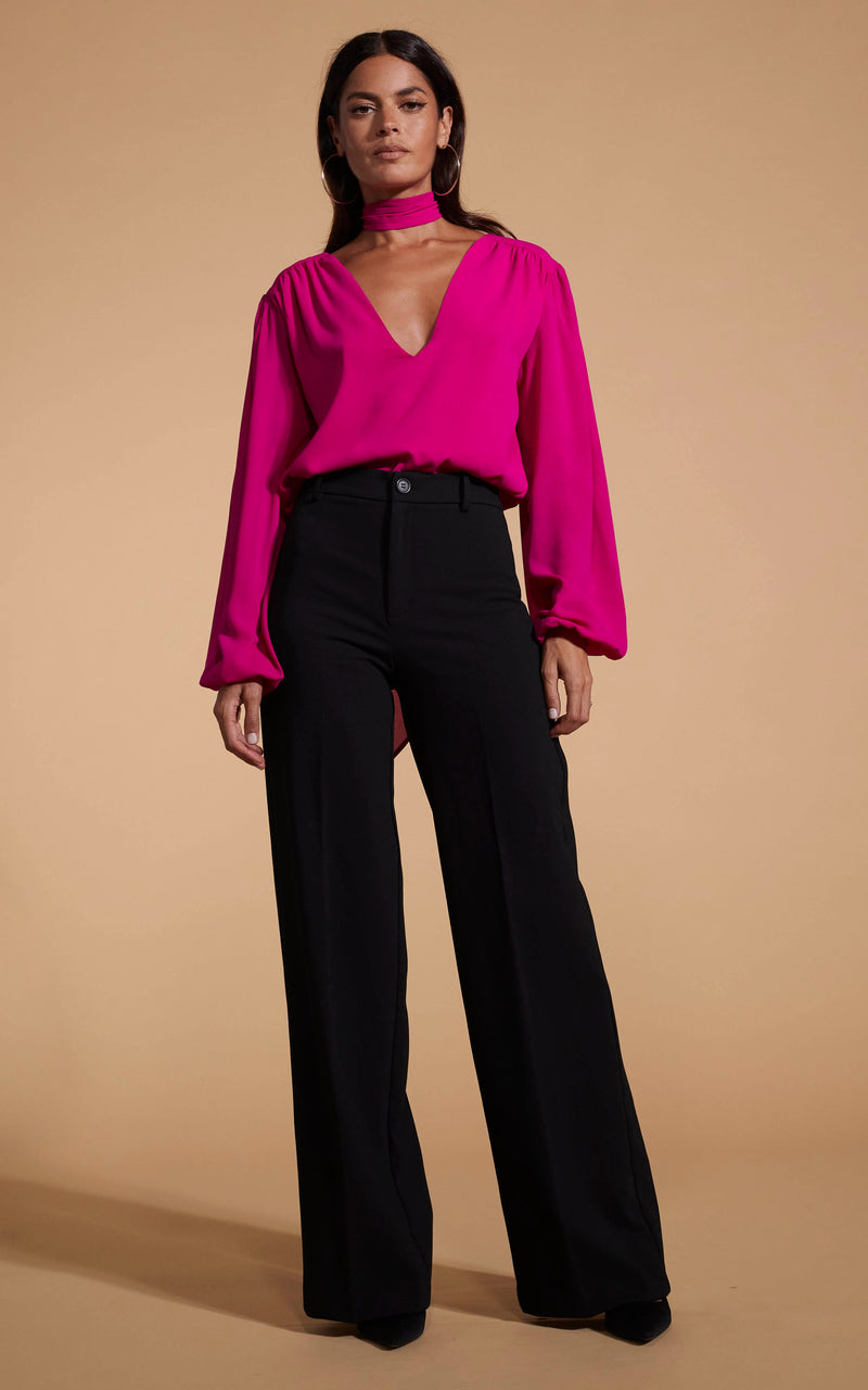 Model faces forward wearing a pink Dancing Leopard V-neck top with black trousers.