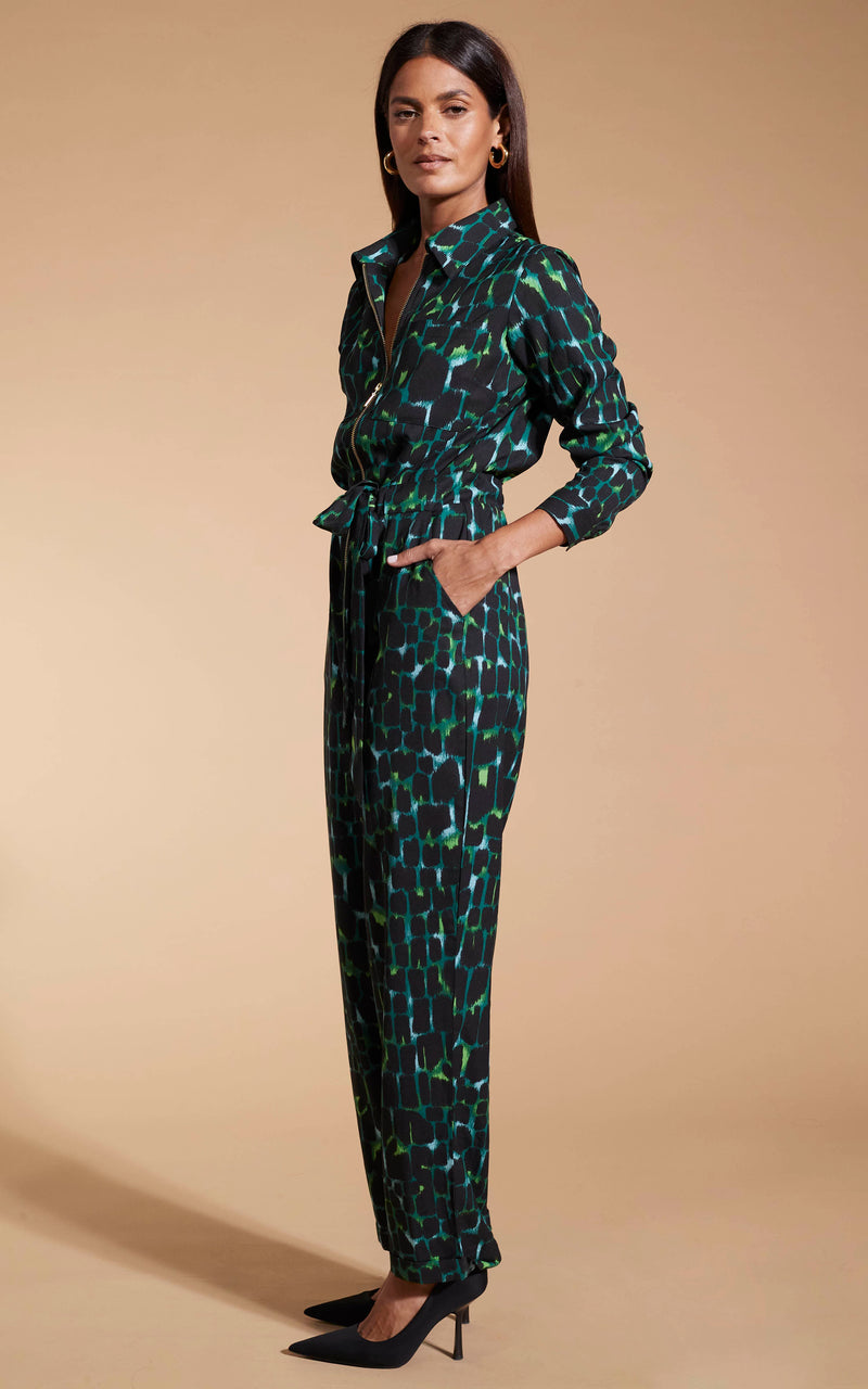 Model facing to the side wearing the green alligator Dancing Leopard jumpsuit.