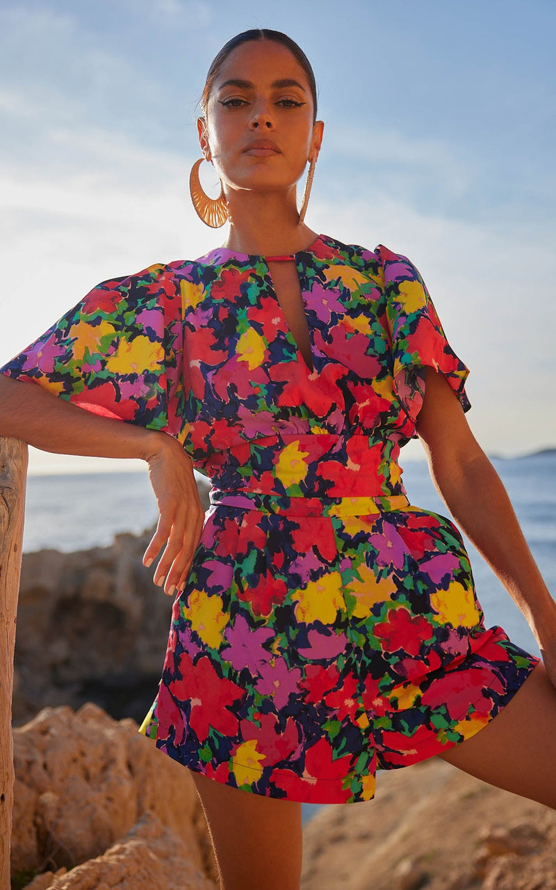 A female model faces forward. She wears a Dancing Leopard colourful, floral printed playsuit.