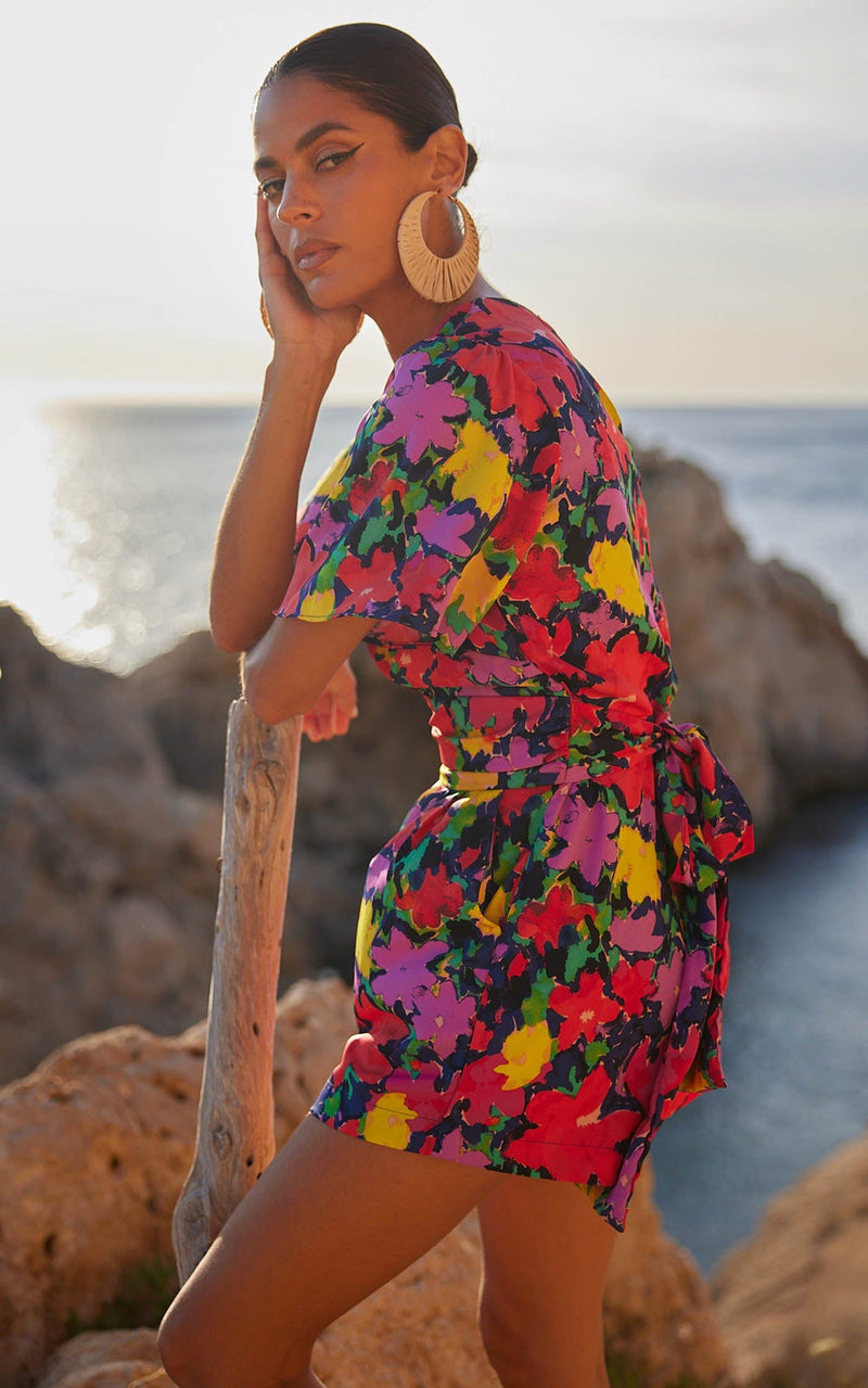 A female model faces forward. She wears a Dancing Leopard colourful, floral printed playsuit.