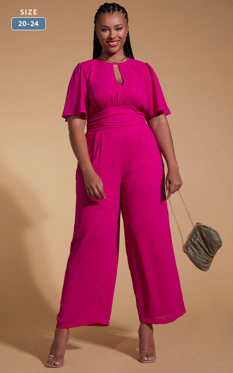 Model faces forward wearing a pink dancing leopard jumpsuit with a gold clutch bag.