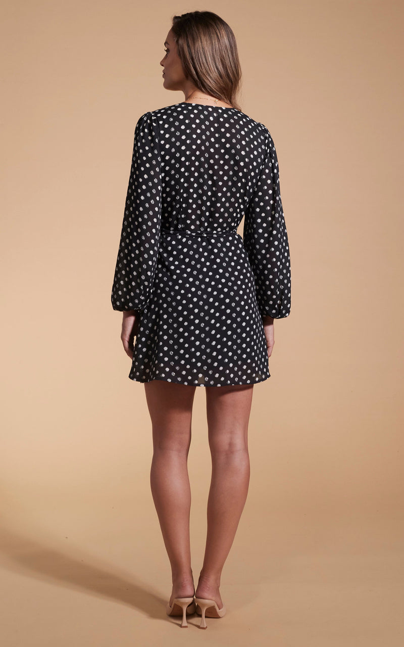 Model faces backwards wearing a short black polka dot Dancing Leopard dress.