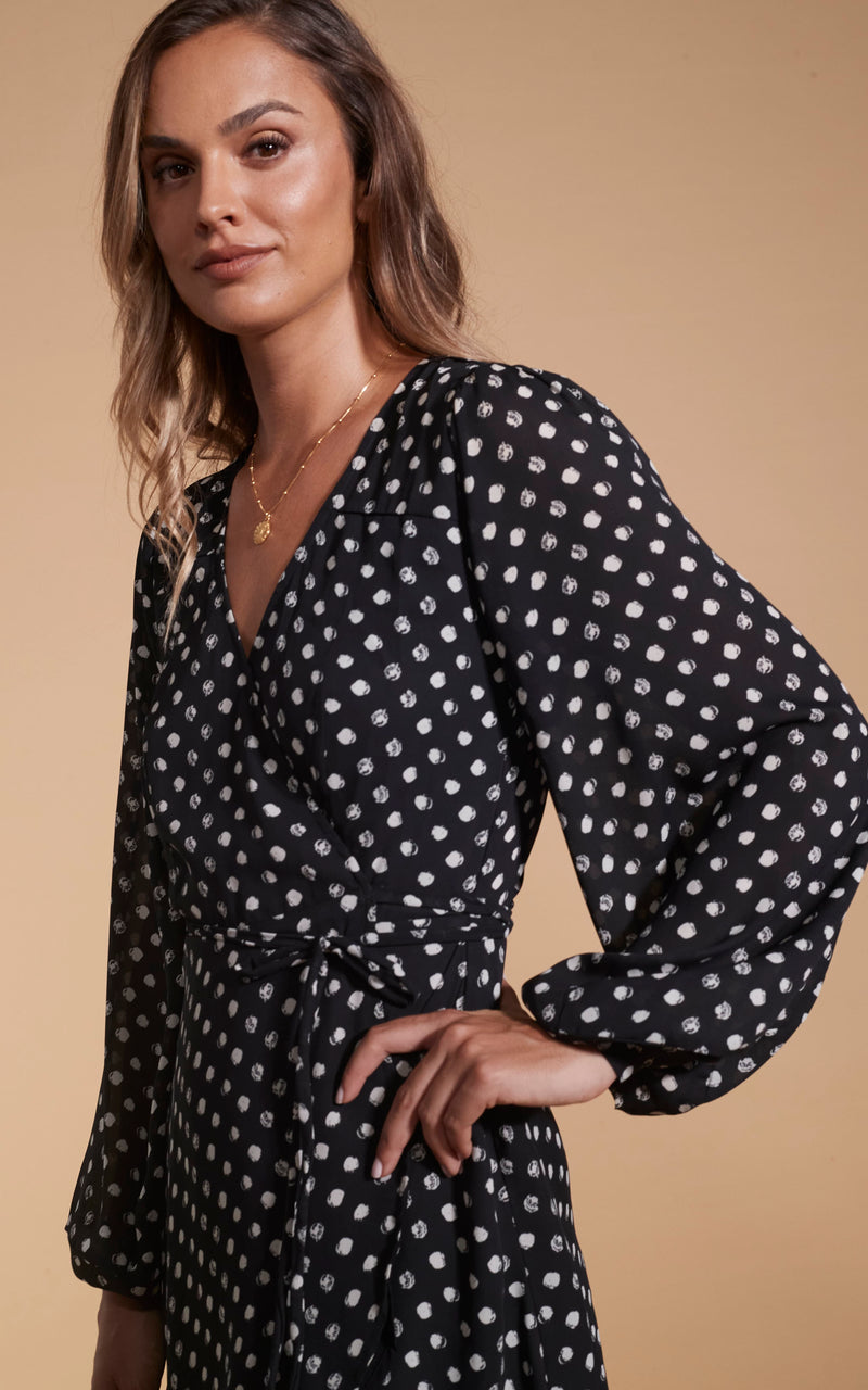 Model faces forward wearing a short black polka dot Dancing Leopard dress.