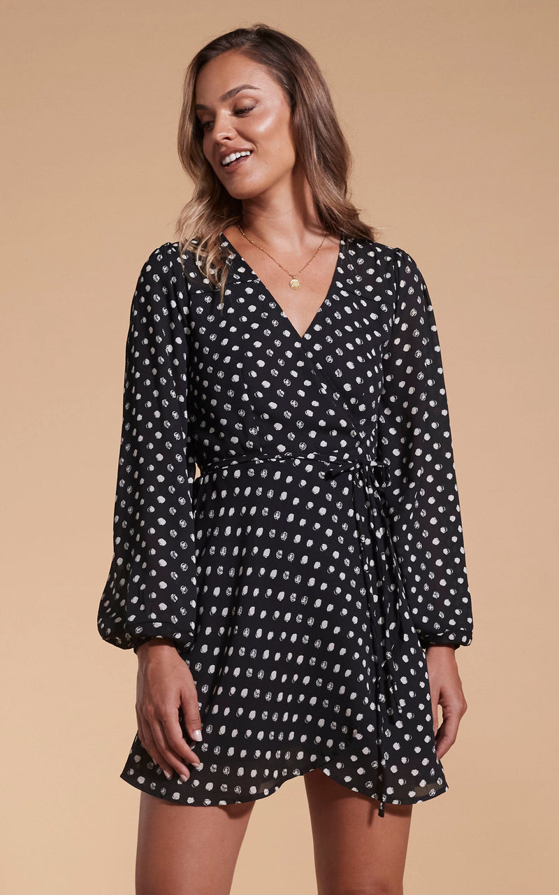 Model faces forward wearing a short black polka dot Dancing Leopard dress.