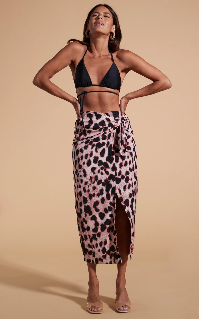 Model stands facing forwards wearing leopard print skirt and black bikini top