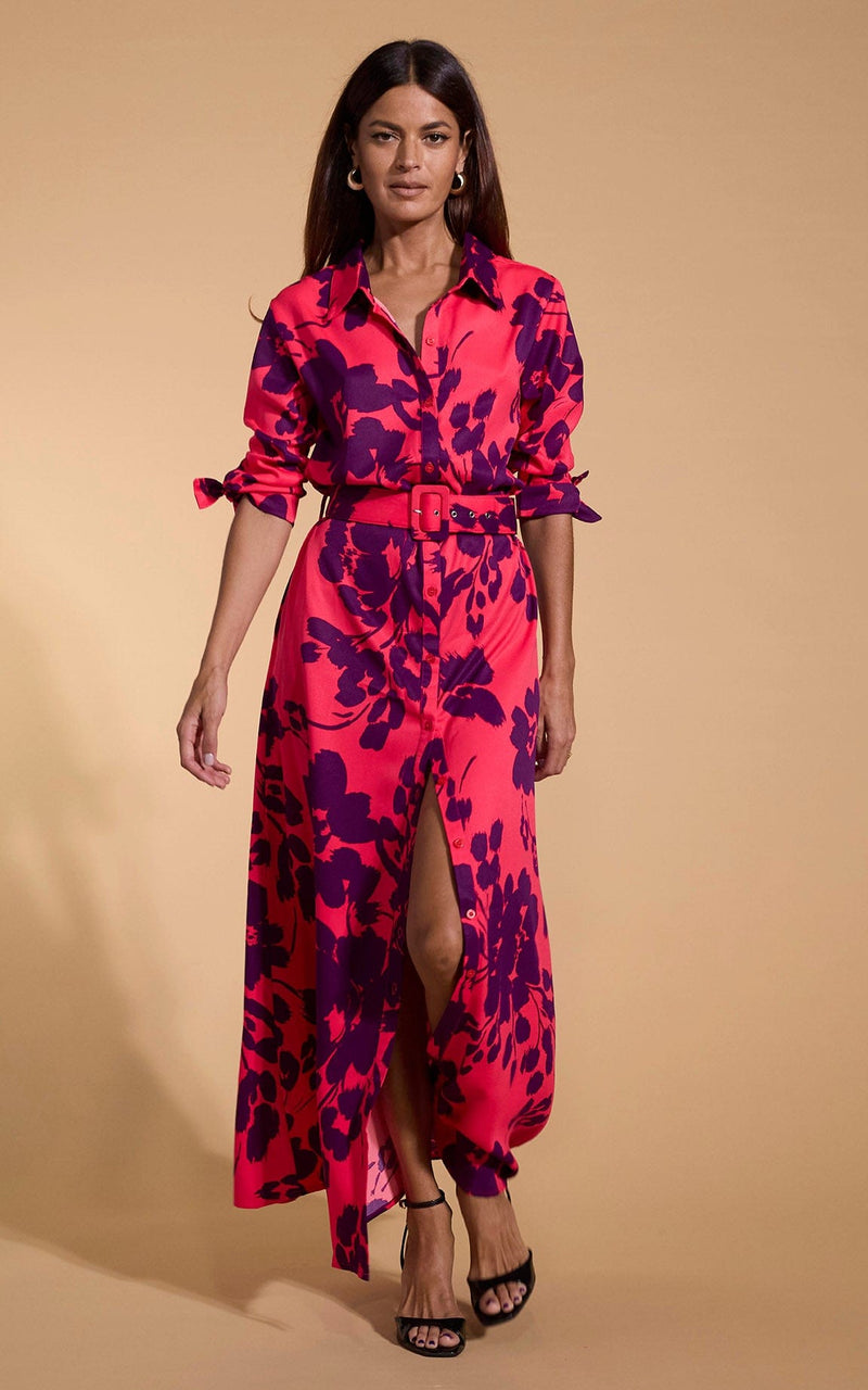 A female model faces forwards. She wears a Dancing Leopard maxi shirt dress. The dress is red with a plum coloured flower print.