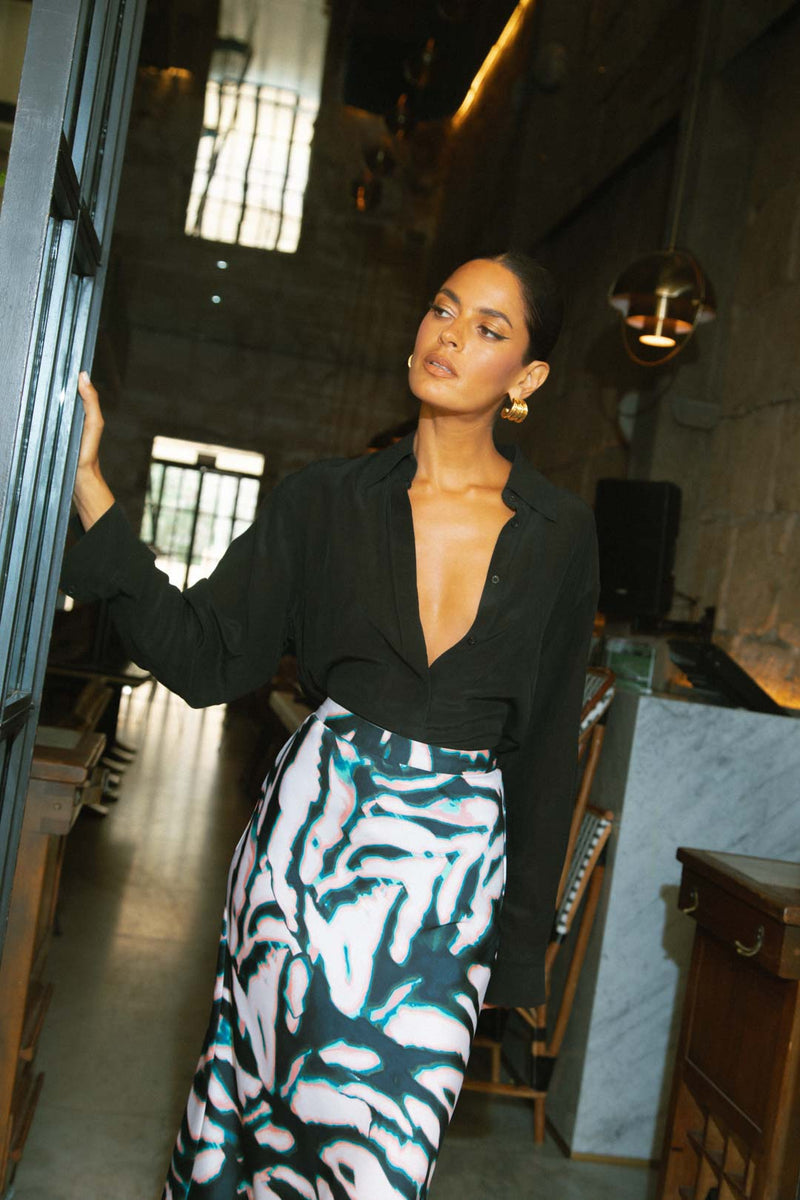 Model faces forward wearing a  zebra print Dancing Leopard skirt with a black shirt.