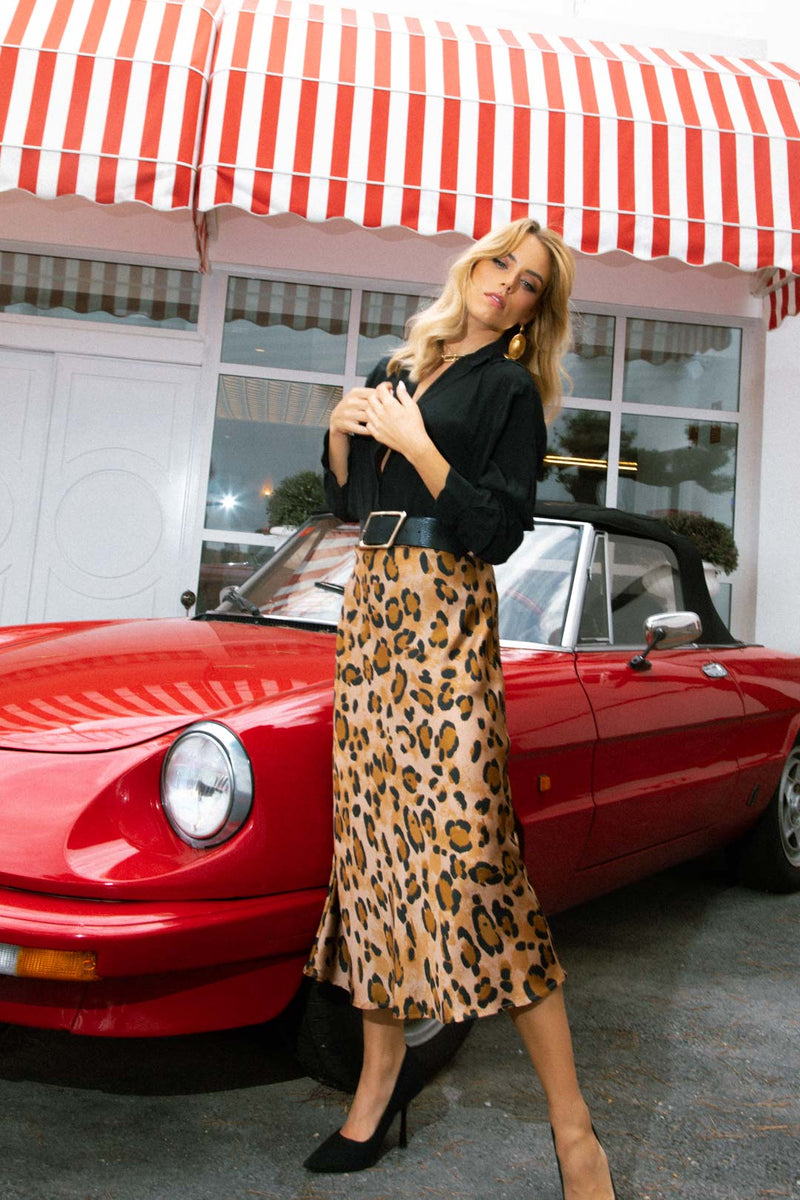 Model facing forward wearing the Lotus Skirt In Leopard with a black shirt and black heels.