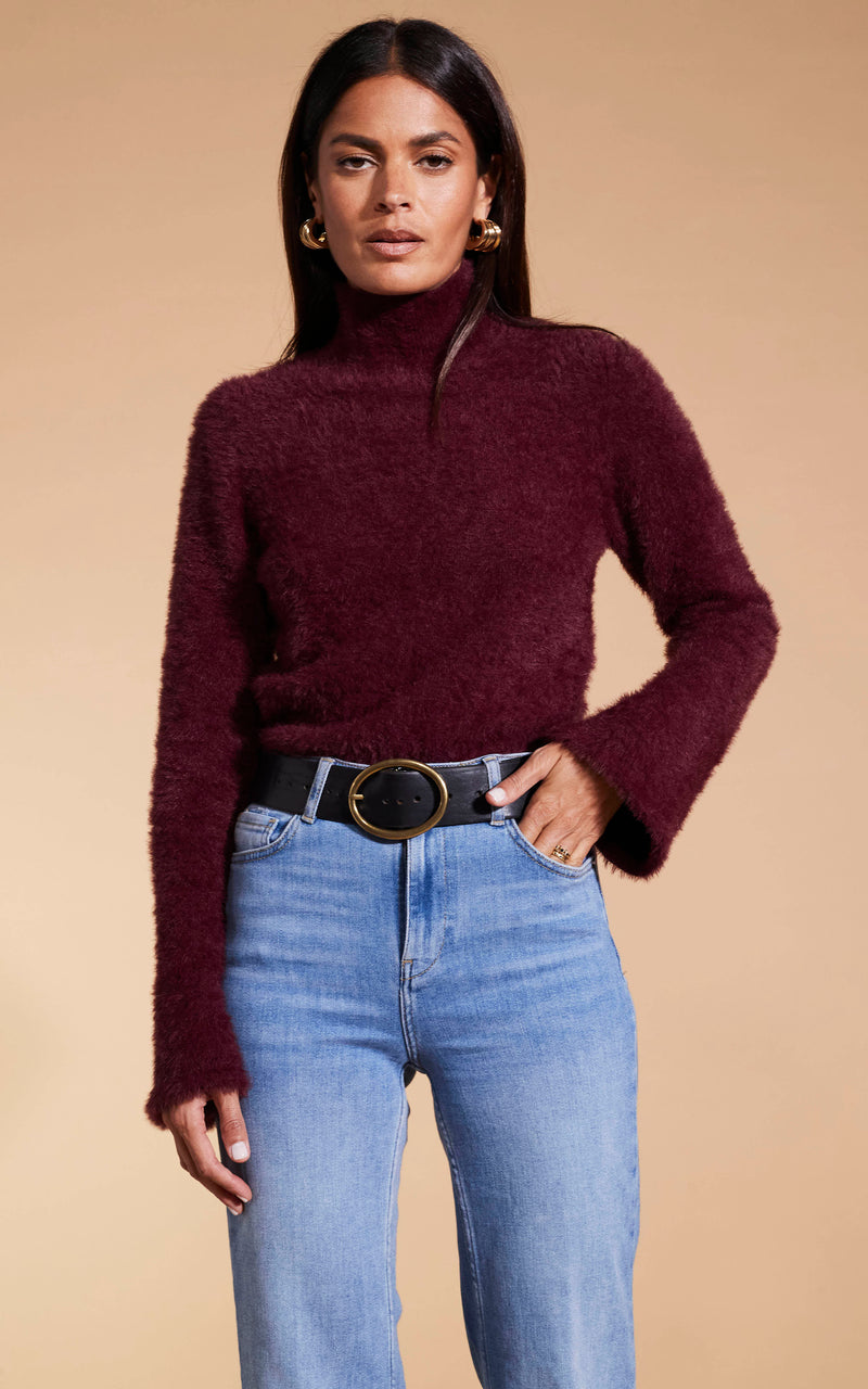 Model faces forward wearing Dancing Leopard burgunday knitted jumper and jeans
