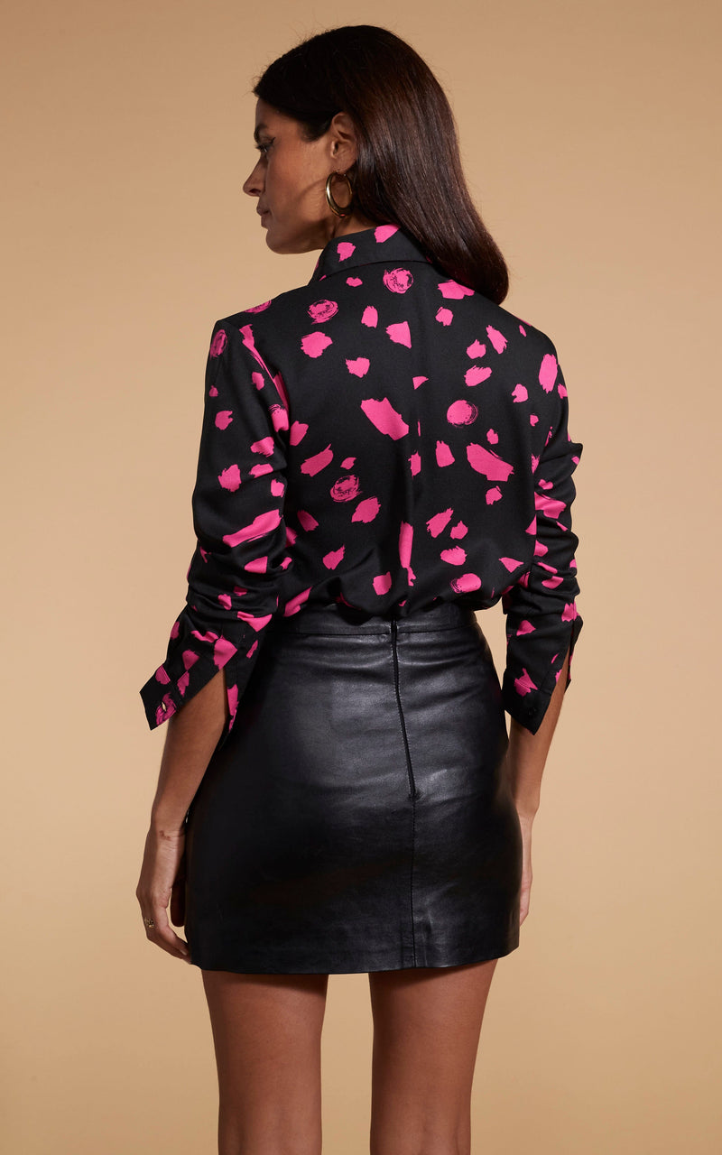 Model faces backwards wearing a black and pink Dancing Leopard shirt with a black skirt.