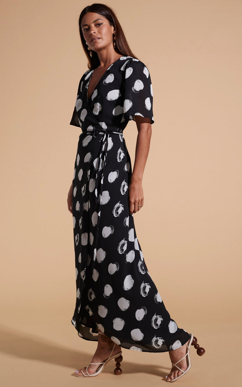 Dancing Leopard model wearing Jenna Maxi Dress In White on Black Dot facing side on