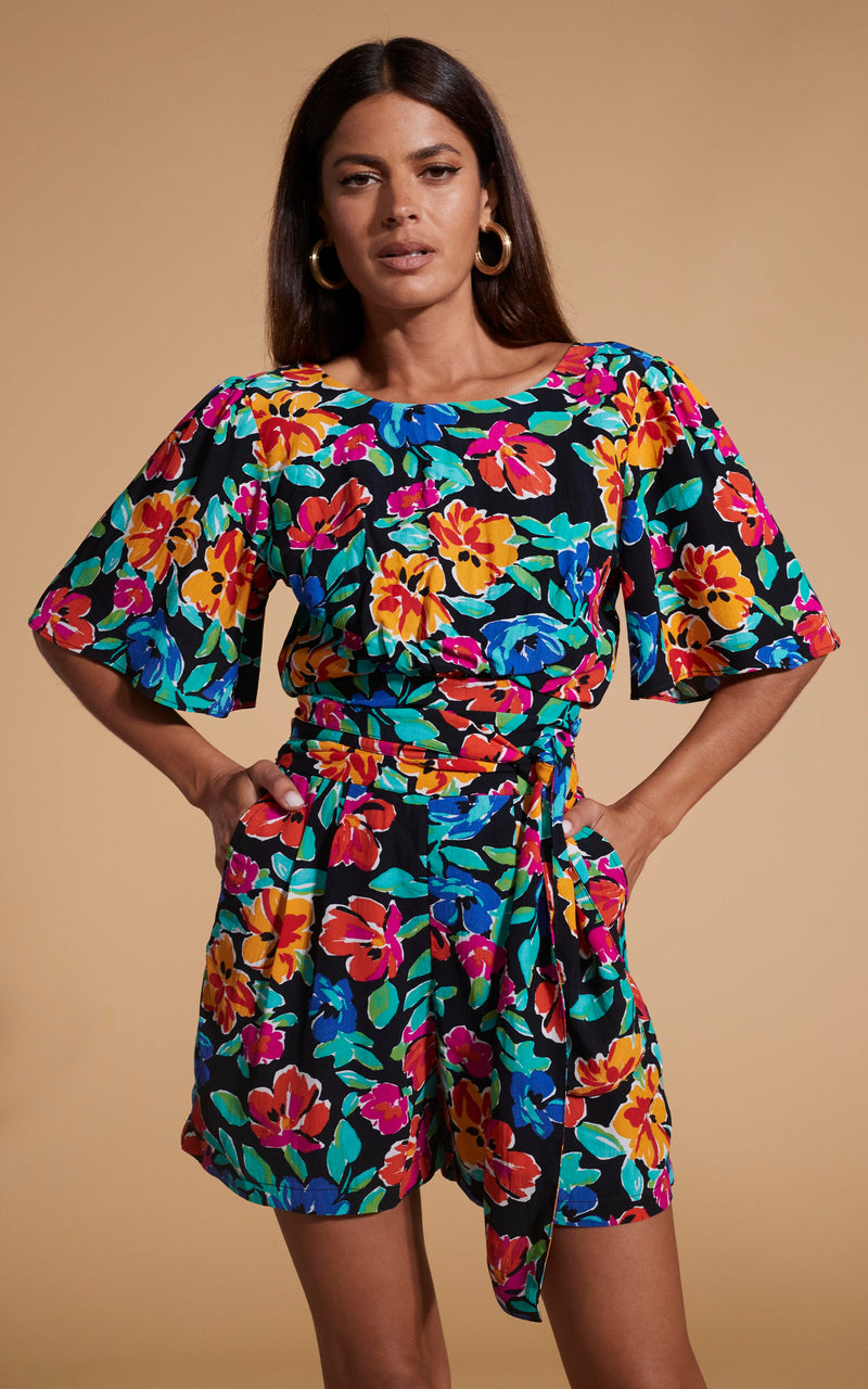 Dancing Leopard model wearing Merlin Playsuit In Vintage Floral posing with hands in pockets