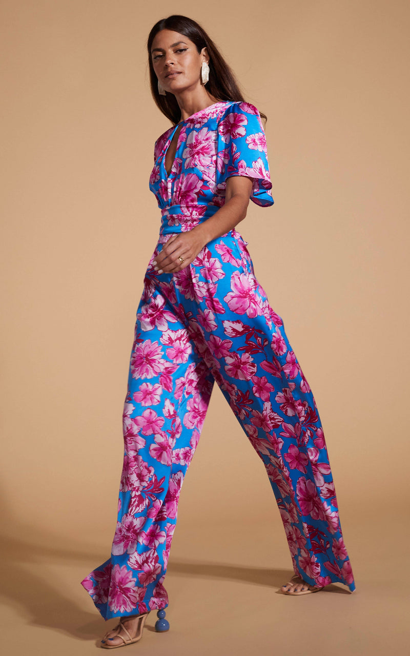 Dancing Leopard model wearing Savannah Jumpsuit In Pink On Blue Floral walking from right to left