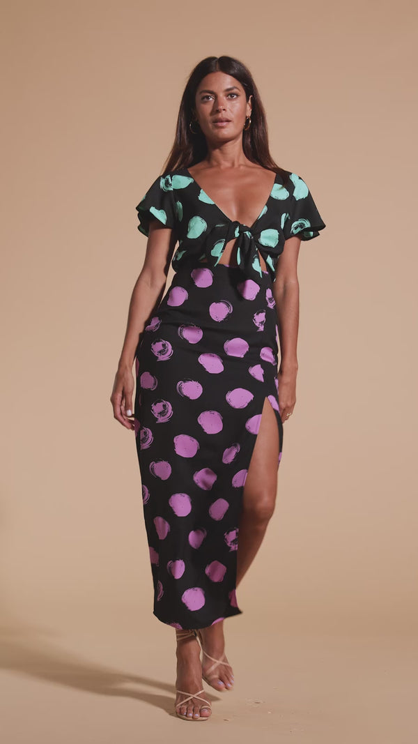 Model walks forwards and twirls wearing polka dot maxi dress with tie-front and heels