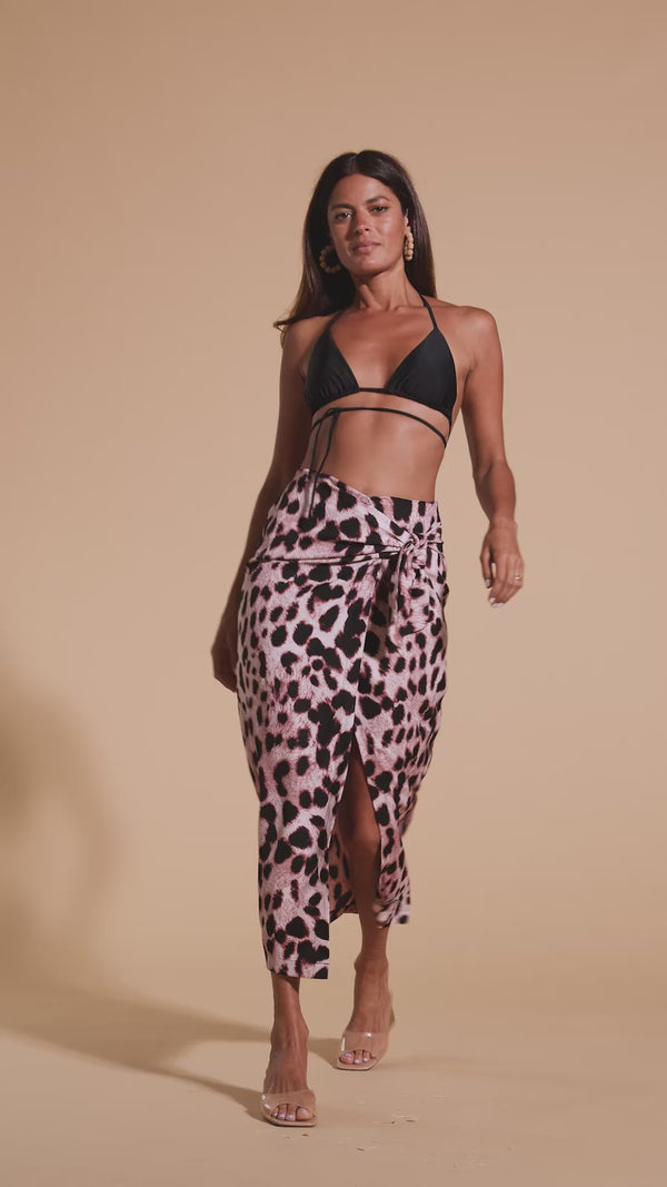 Model walks forwards wearing leopard print skirt and black bikini top
