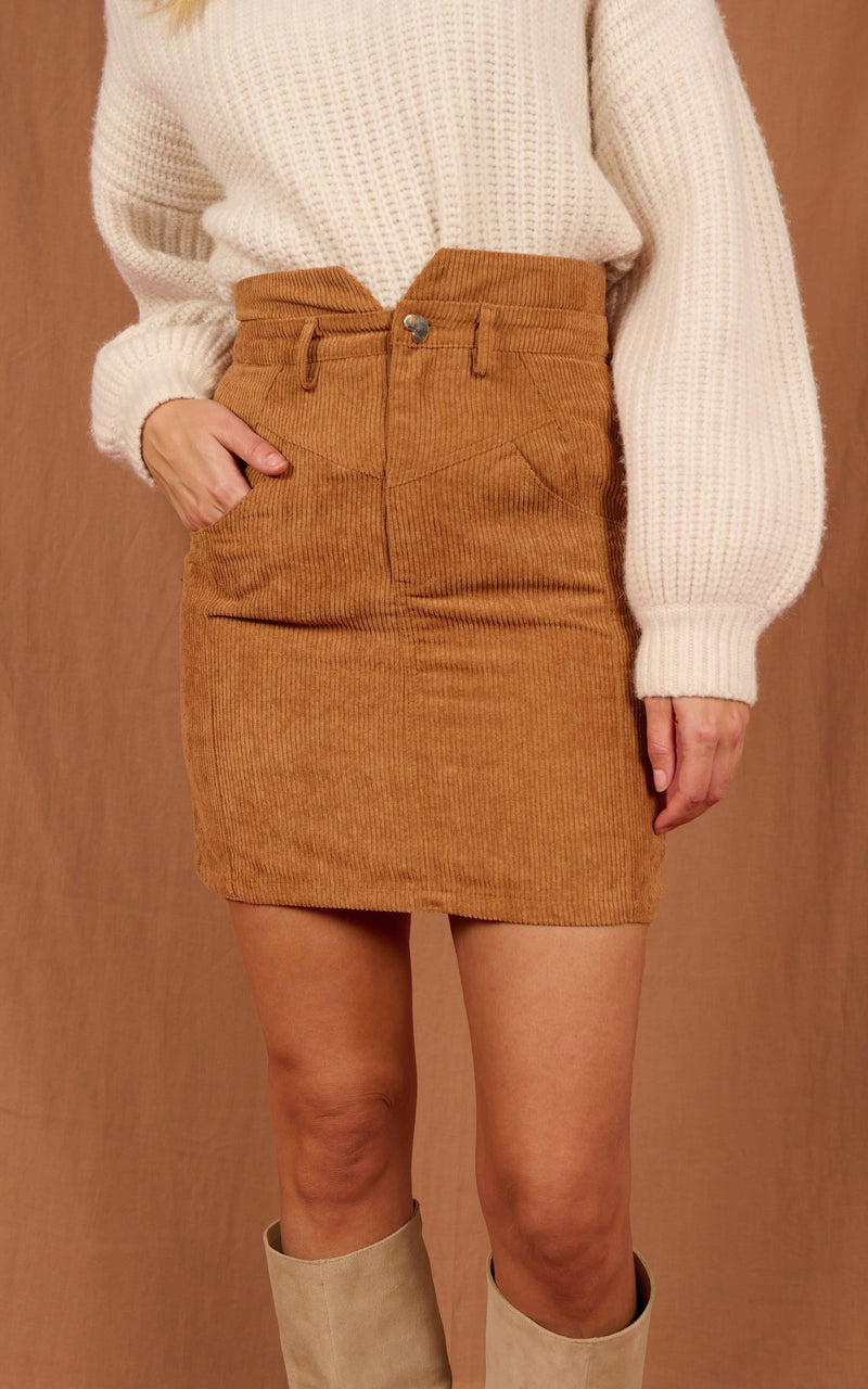 Close up of Dancing Leopard model standing forwards wearing Nikeeta mini skirt in tan with white jumper