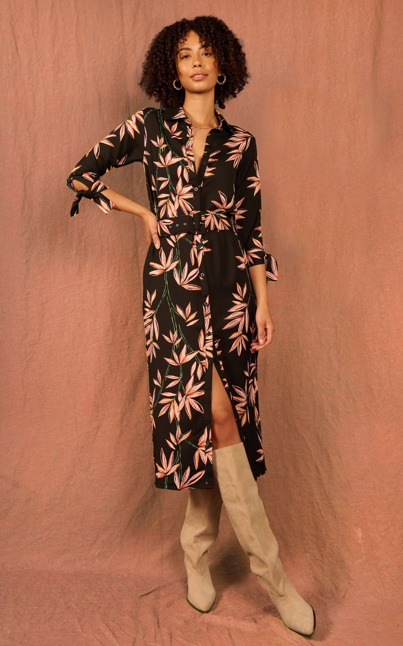 Dancing Leopard model standing with hand on hip wearing a midi shirt dove dress in bamboo on black print and tan knee high boots