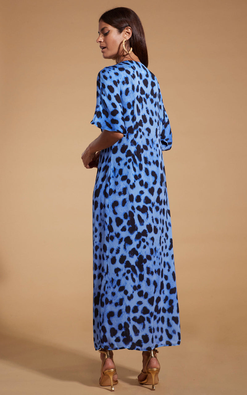 Dancing Leopard model wearing Makuna Kaftan In Bright Blue Leopard facing away to show back of dress