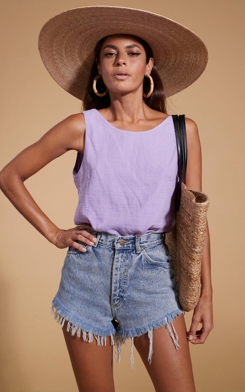 Dancing Leopard model wearing HALO Guava Twist Top in Lilac with a straw bag and hat