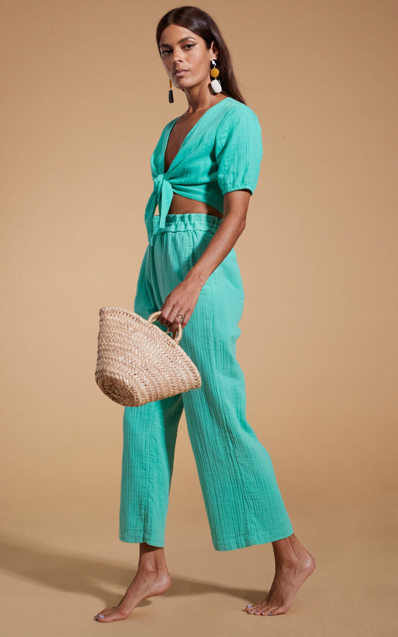 Dancing Leopard model wearing HALO Indra Tie Top in Mint Green walking with straw bag in hand