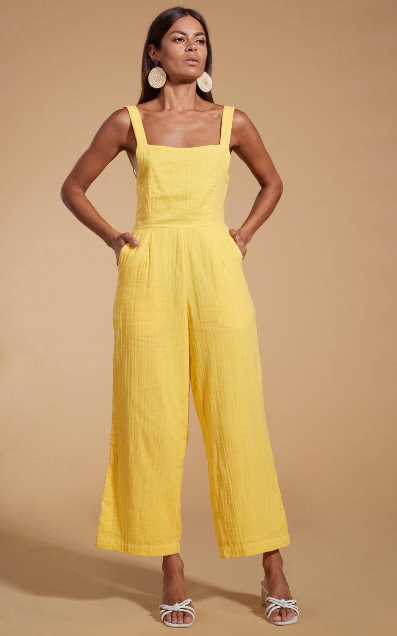 Dancing Leopard model wearing HALO Kimani Twist Back Jumpsuit in Primrose Yellow posed with hands in pockets