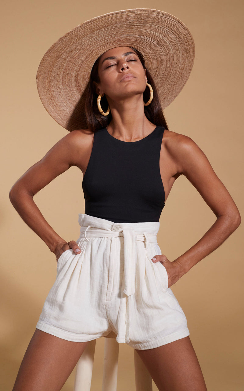 Dancing Leopard model wearing HALO Nessie High-Waist Shorts in Cream with black top posed sat on a stool