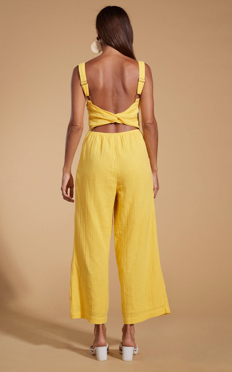 Dancing Leopard model wearing HALO Kimani Twist Back Jumpsuit in Primrose Yellow facing away to shot back of jumpsuit