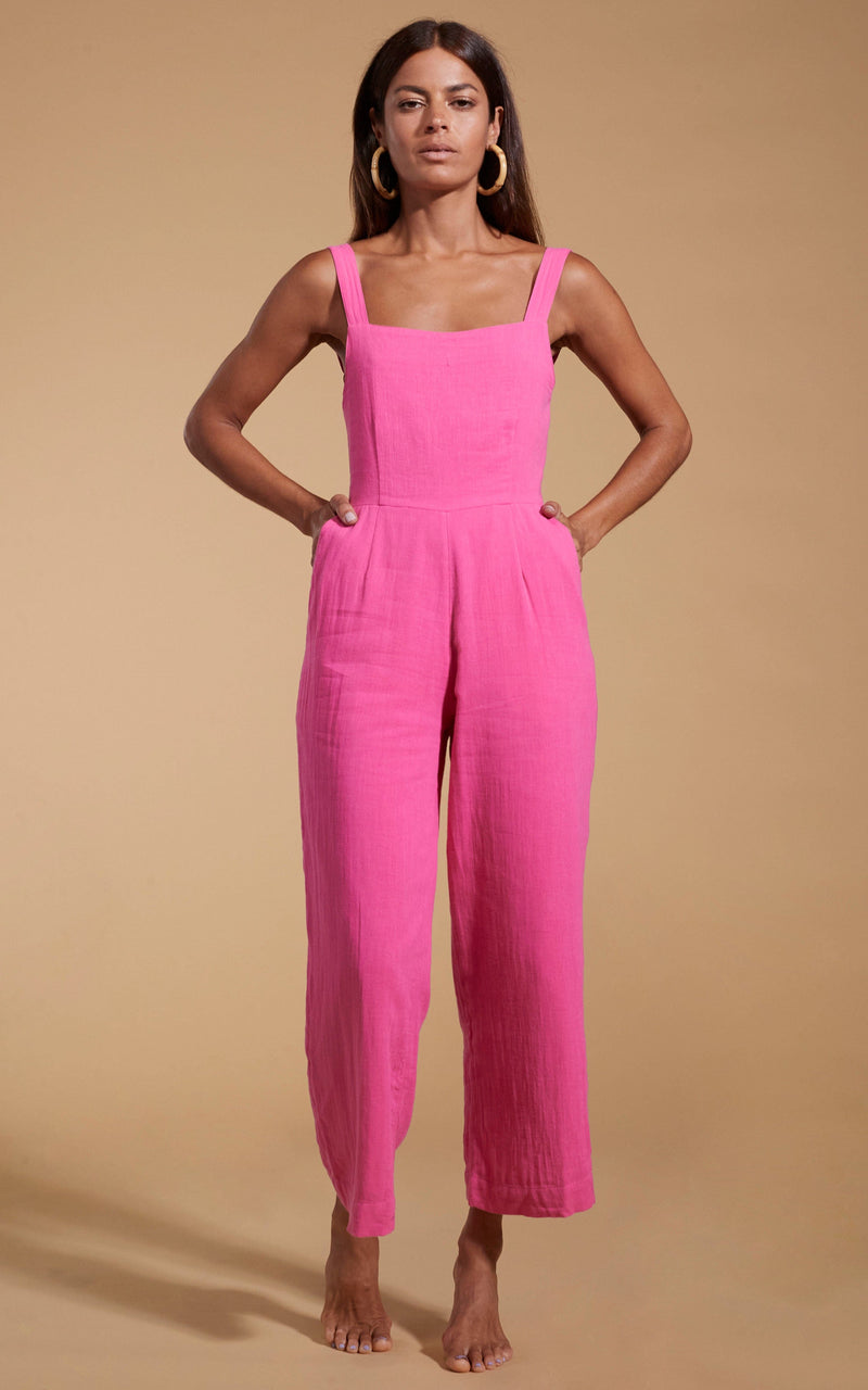 Dancing Leopard model wearing HALO Kimani Twist Back Jumpsuit in Magenta posed with hands in pockets
