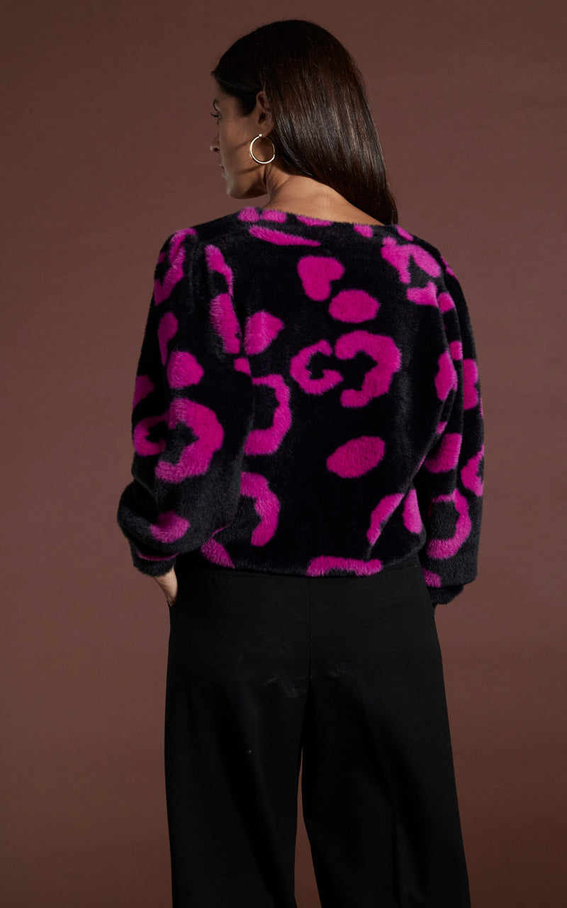 Dancing leopard model Sarah standing with back to camera wearing Bambino cardigan in cerise on black leopard 