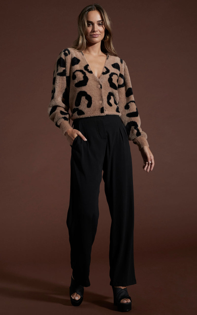 Dancing leopard model Belen wearing bambino cardigan in black on mocha leopard with black trousers