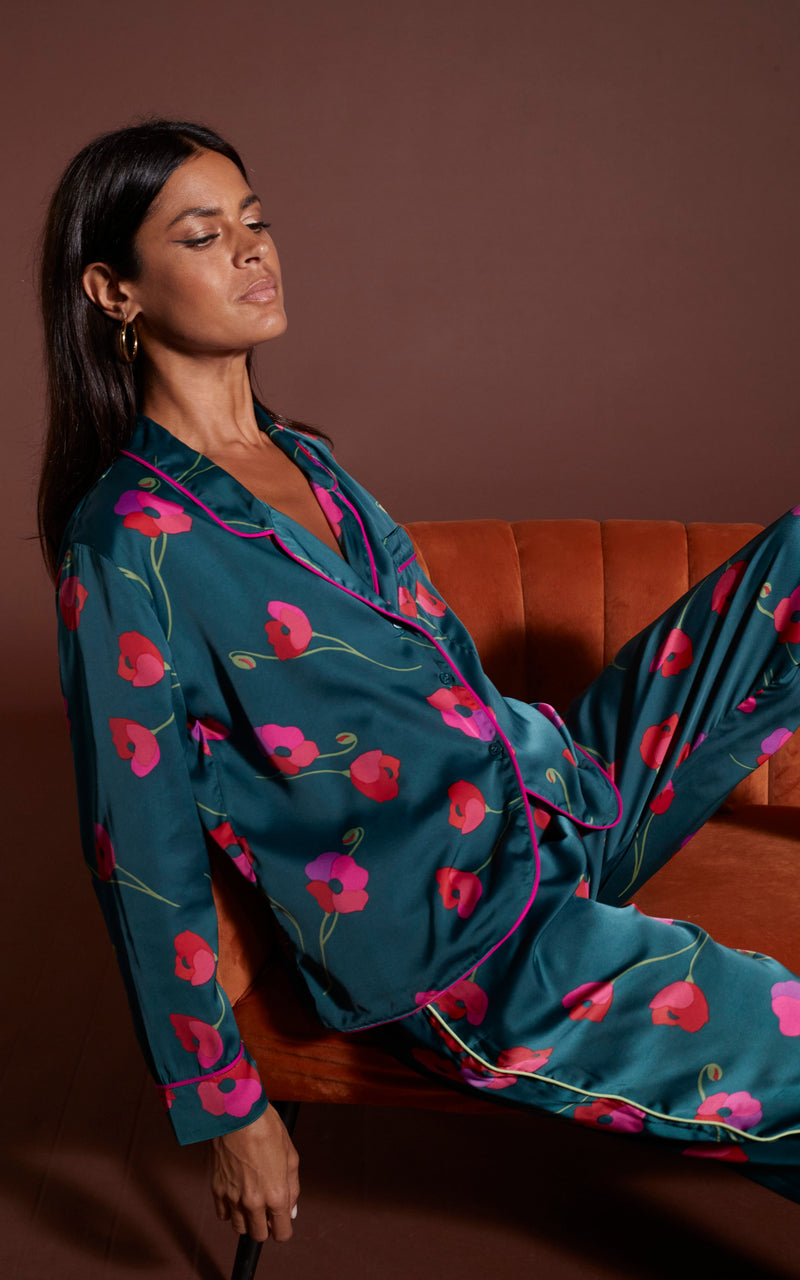 Dancing Leopard model wearing Cosmos Satin Long Leg PJ Set in Poppies on Dark Green slouched on orange couch