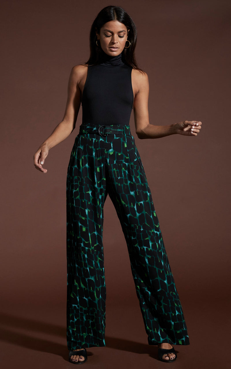 Dancing leopard model standing wearing Jesse trousers in green alligator print