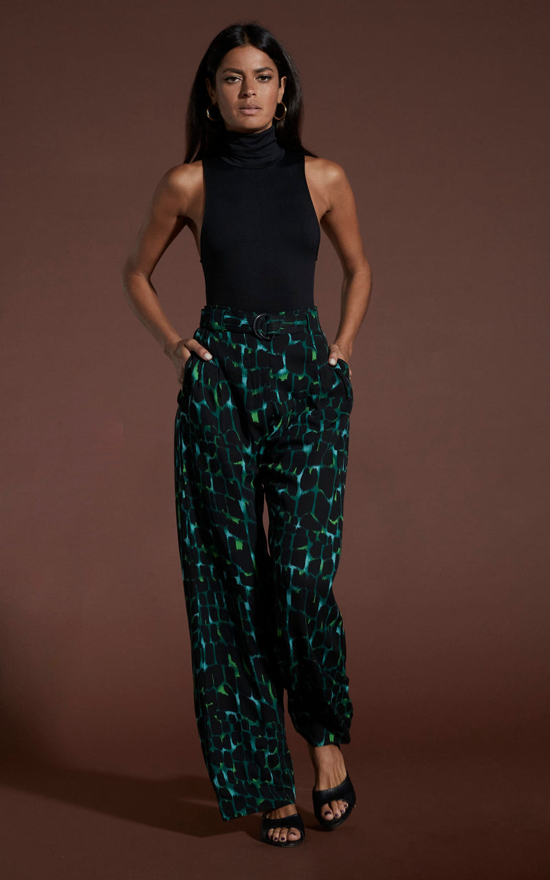 Dancing leopard model walking towards camera with hands in pockets wearing Jesse trousers in green alligator and black top