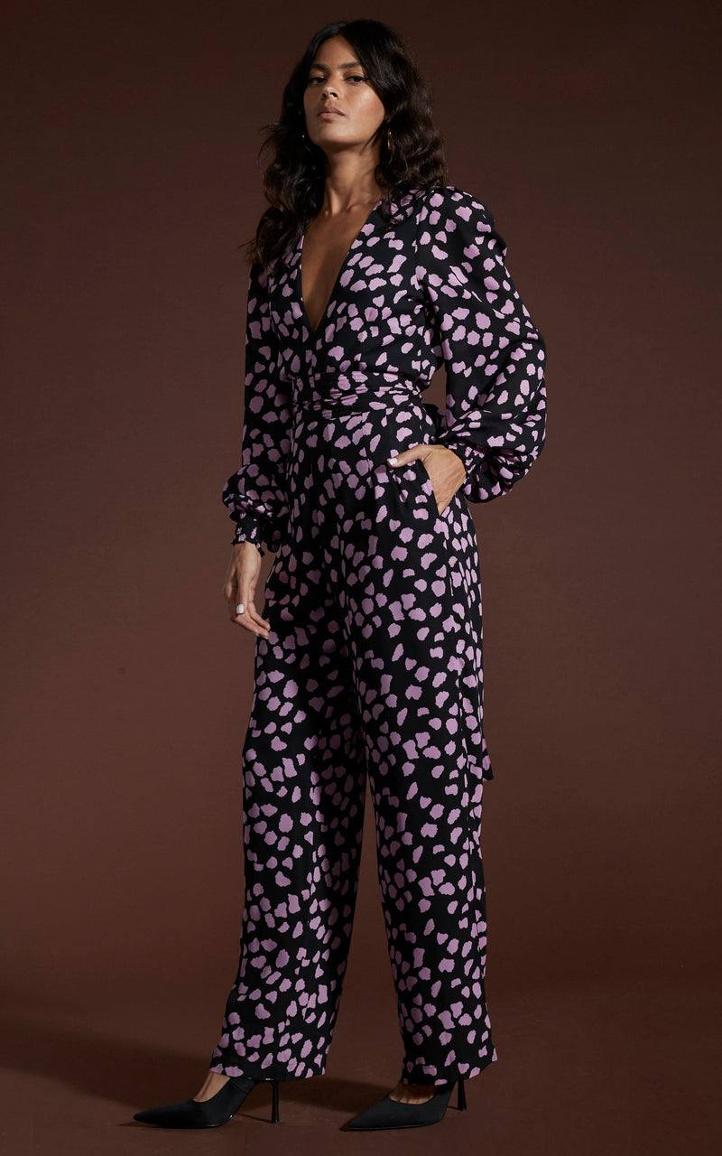 Dancing Leopard model wearing Holly Jumpsuit In Pink On Black Cloud posed with one hand in pocket