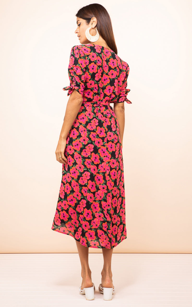 Dancing Leopard model faces backwards wearing Olivera Midi Dress in pink and black hibiscus print