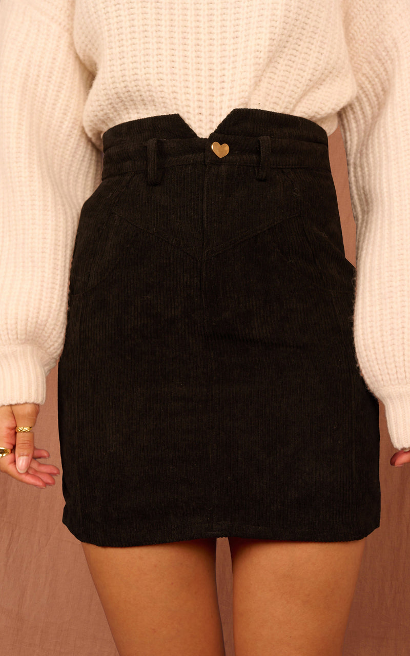 Close up of Dancing Leopard model wearing black Nikeeta skirt with cream jumper