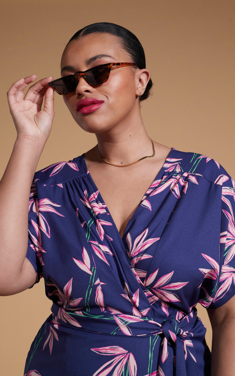 close up of Dancing Leopard model wearing Kansas Mini Wrap Dress In Bamboo Navy Base posing holding sunglasses