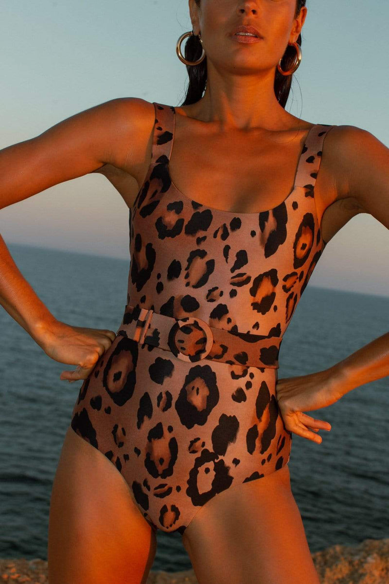 Dancing Leopard model faces forwards standing on beach wearing HALO Kiara Belted Swimsuit in Leopard Print
