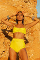 Dancing Leopard model faces forward and stands on beach wearing HALO Juniper bikini brief and Lalita bikini top in yellow