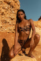 Dancing Leopard model crouches down while wearing leopard print bikini on beach