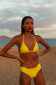 Dancing Leopard model faces forwards wearing yellow bikini top and bottoms standing on beach
