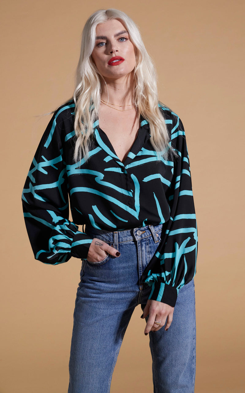 Dancing Leopard model wearing Dixie Balloon Sleeve Shirt In Blue Strokes On Black with blue jeans