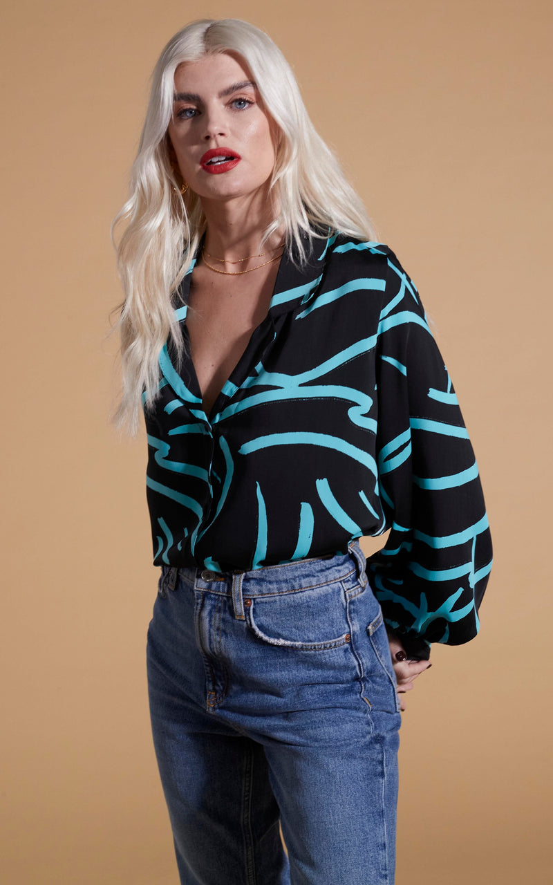 Dancing Leopard model wearing Dixie Balloon Sleeve Shirt In Blue Strokes On Black and blue jeans posed with hands behind back