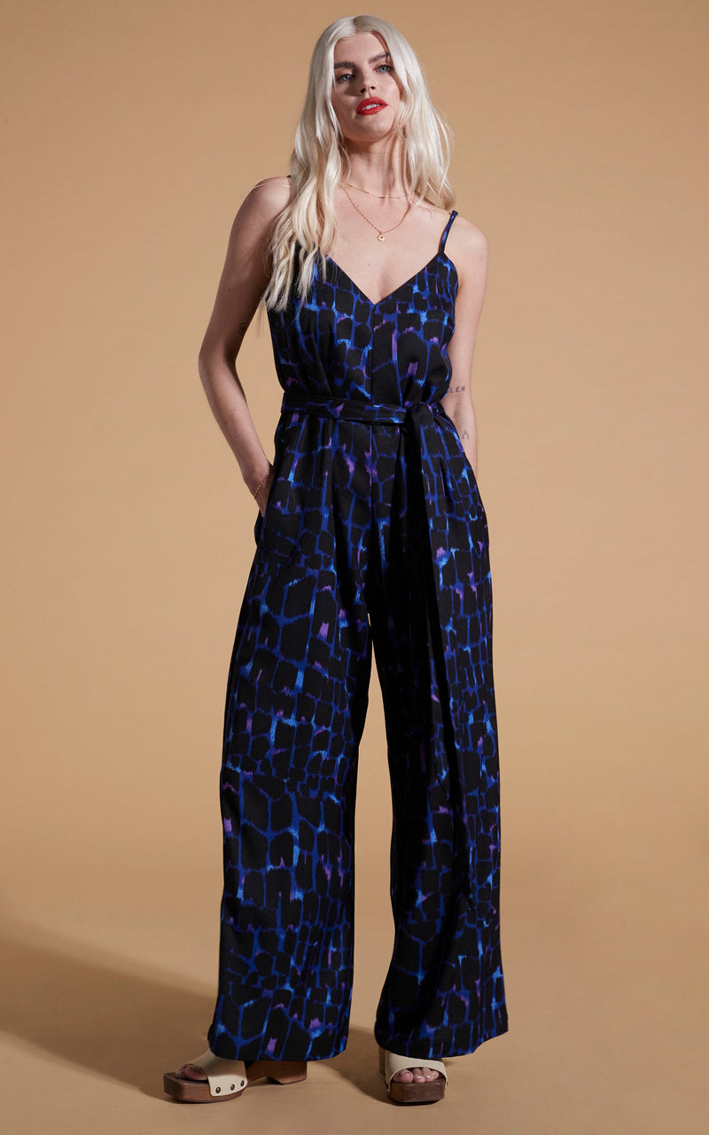 Dancing Leopard model wearing Gabriella Jumpsuit In Blue Alligator posed with hand in pocket